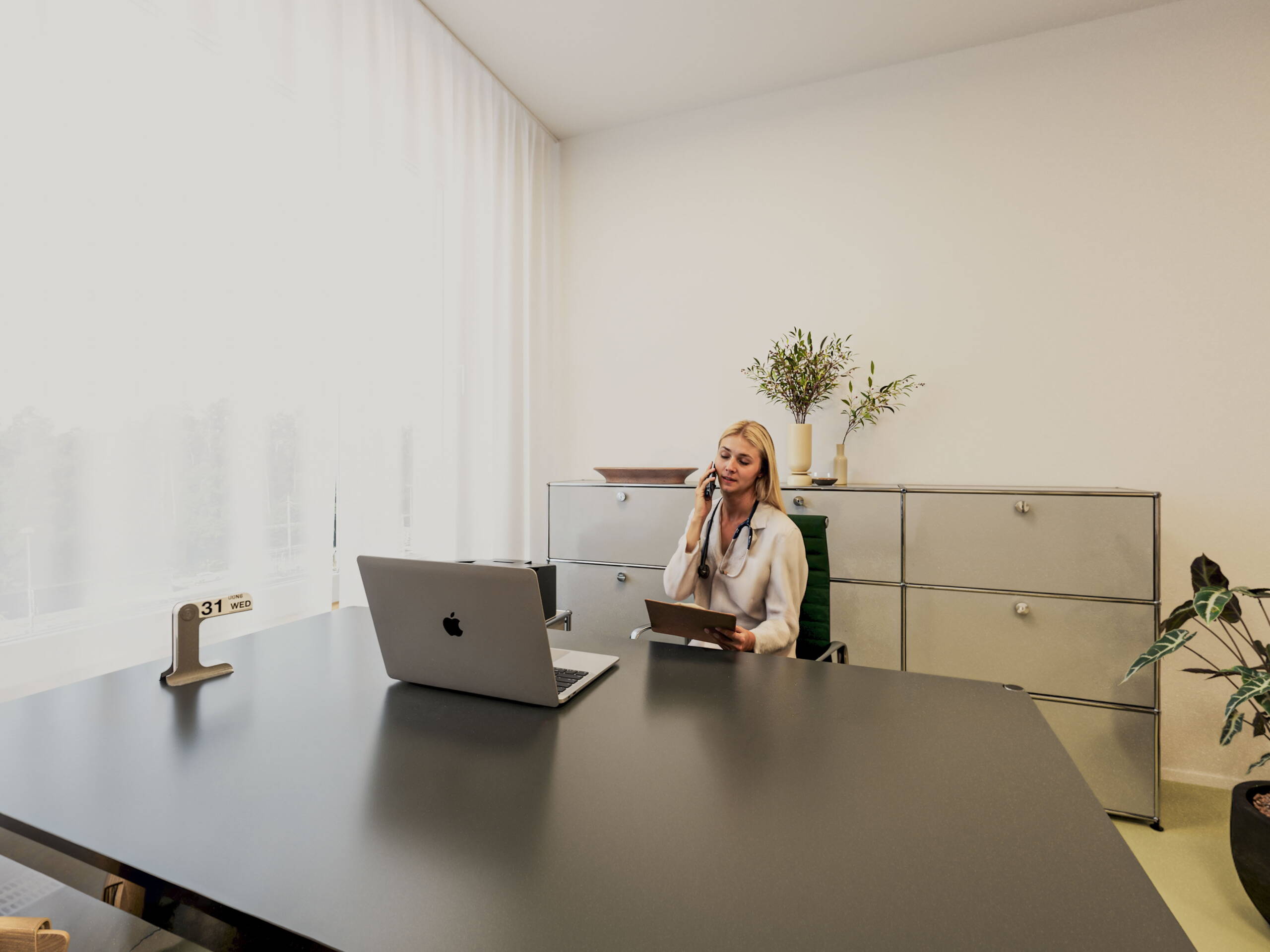 vitaone Arzpraxis Büro, Frau mit Laptop am Telefon